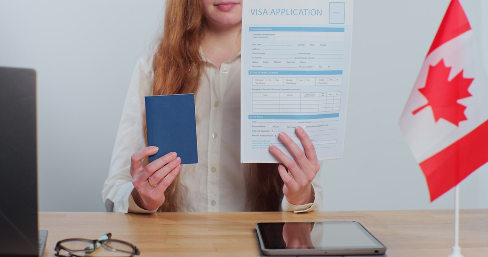 Canada Visa Processing Time: A picture a Canadian Consular officer officer holding Visa application form and passport.