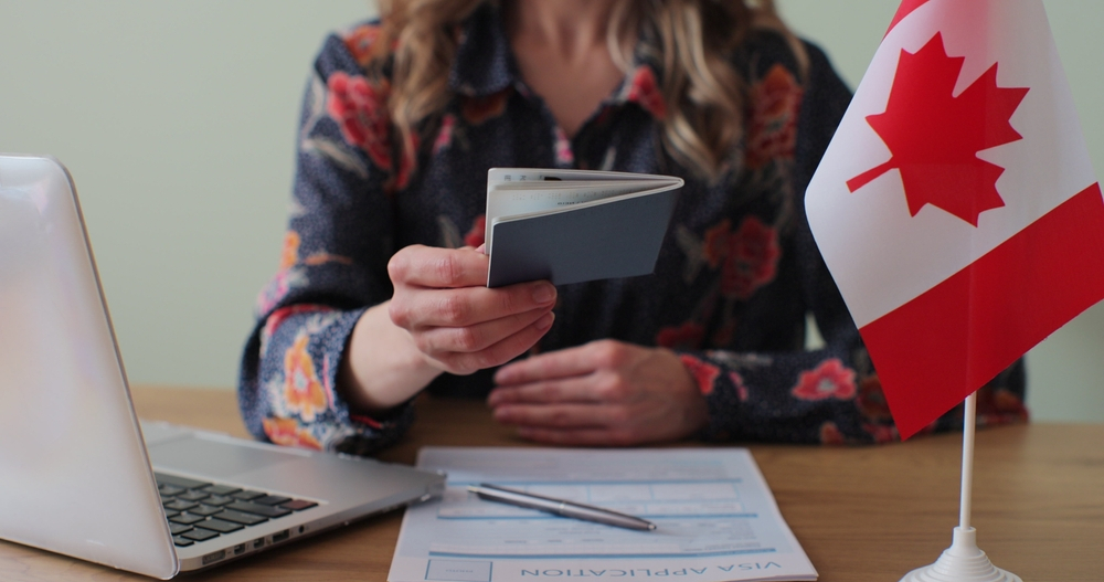 Canada Visa Requirements: A picture showing a Canadian Embassy worker over passport with approved visa to applicant who sailed through requirements