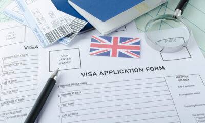 UK Visitor Visa Application: A picture showing Visa application form, passports, tickets, UK flag, magnifying glass on the world map