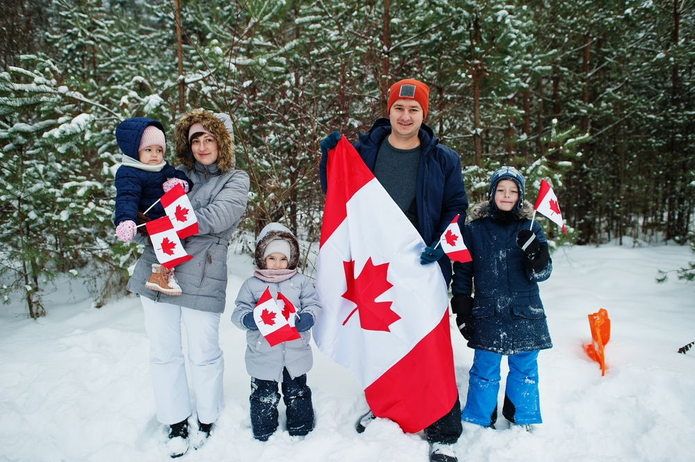 Canada Permanent Residency: A picture showing a Canadian family holding flags after bagging permanent Residency status.