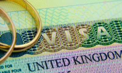 UK Spouse Visa vs Unmarried Partner Visa:UK entry visa sticker in a passport and the rings placed on top. Concept for Partner and Spouse visa UK.