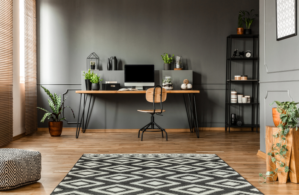 The Ultimate Guide to Setting Up a Productive Home Office: Patterned carpet and pouf in simple grey workspace interior with computer monitor on desk. 