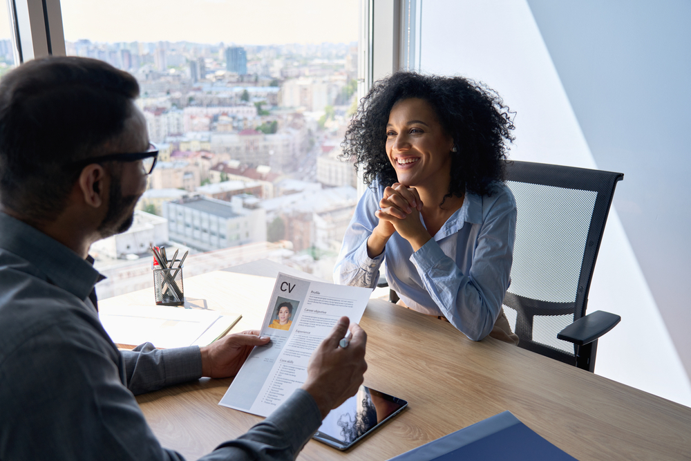 The 10 Worst Ways to Botch Your UK Job Search: Friendly interview between businessman hr director holding paper cv hiring for job female applicant manager