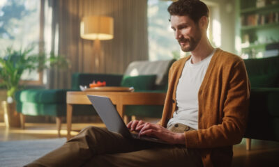 Worst Remote Work Habits That Kill Productivity: Handsome Happy Man Using Laptop at Home for Remote Work.