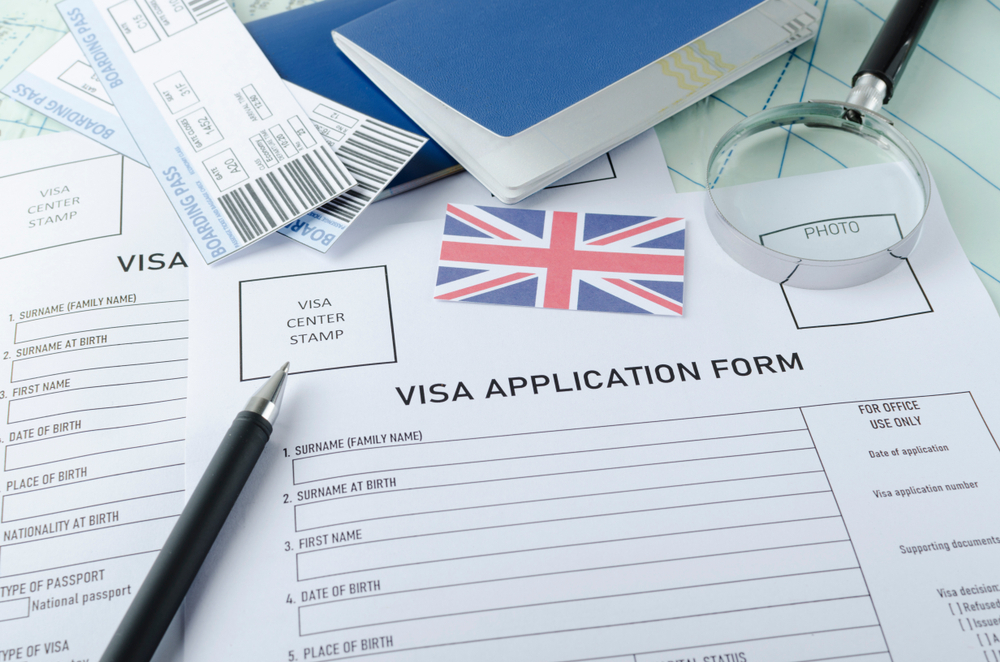 7 Things to Avoid During the UK Visa Application Process: Visa application form, passports, tickets,English flag, magnifying glass on the world map. 
