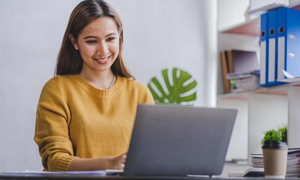 Secrets to Advancing Your Career in a Remote Job: A happy female freelancer working on a laptop at home office
