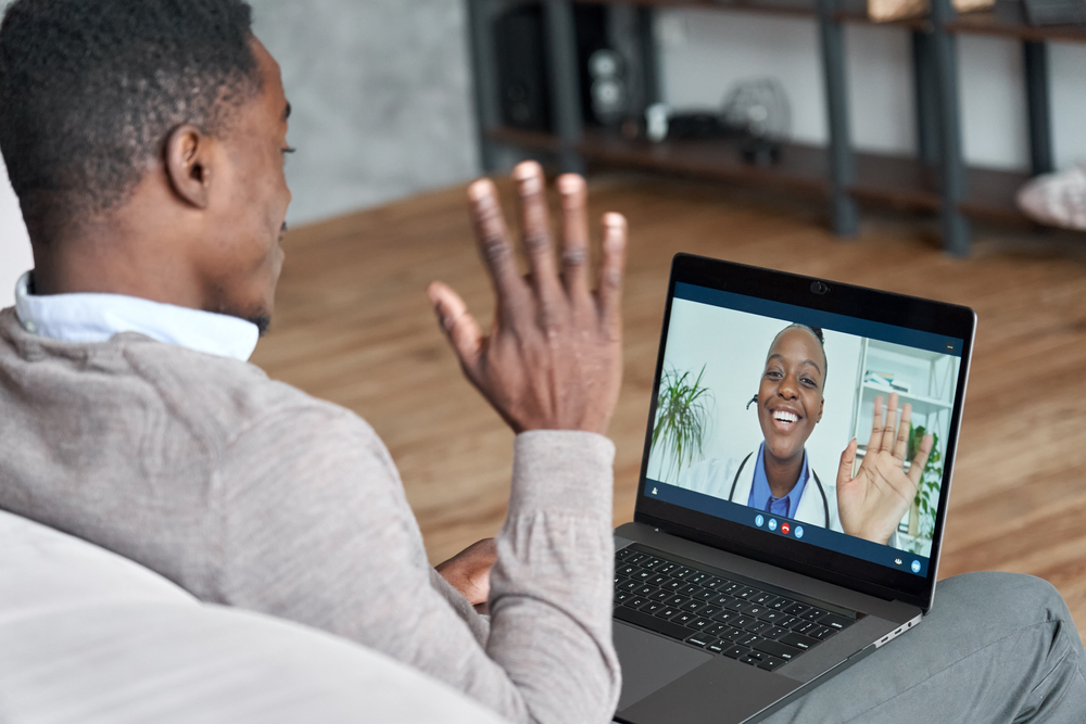Things to Know Before Relocating for a Remote Job: A Male black patient talking on conference video call to female african doctor. Virtual therapist consulting young man during online appointment on laptop at home. 