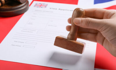 7 Things to Avoid During the UK Visa Application Process: Immigration to United Kingdom. Woman stamping visa application form on flag