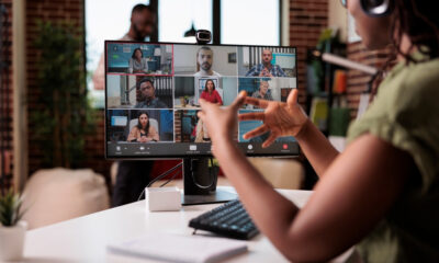 Secrets to Successfully Collaborating with a Remote Team: Picture of a startup employee working from home gesturing in video conference with colleagues at the desk.