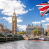 Visa Pitfalls That Can Derail Your UK Dreams: Big Ben with bridge over Thames and flag of England against blue sky in London, England, UK