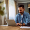 The Essential Guide to Remote Job Performance Reviews: Picture of a focused male freelancer working remotely from home.