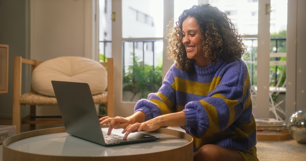 Work from Home Pitfalls and How to Avoid Them: Picture of a happy lady working remotely on a laptop.