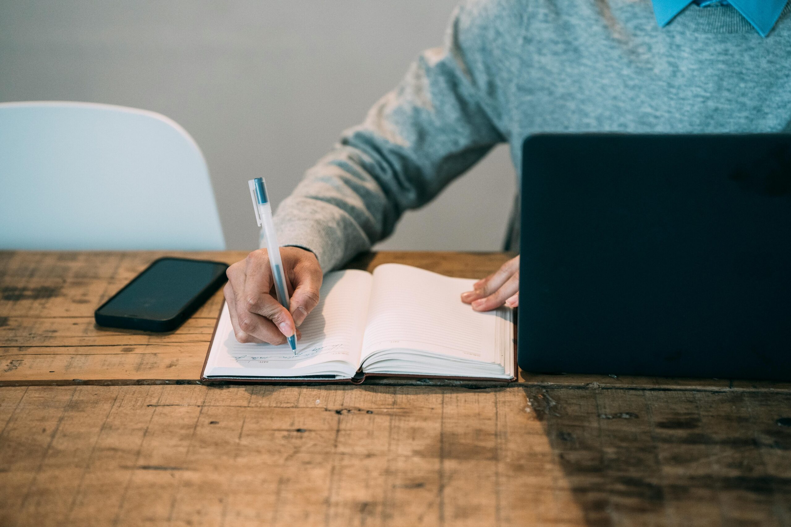 Remote Job Scams to Avoid at All Costs: Picture showing a faceless man taking note from the laptop.