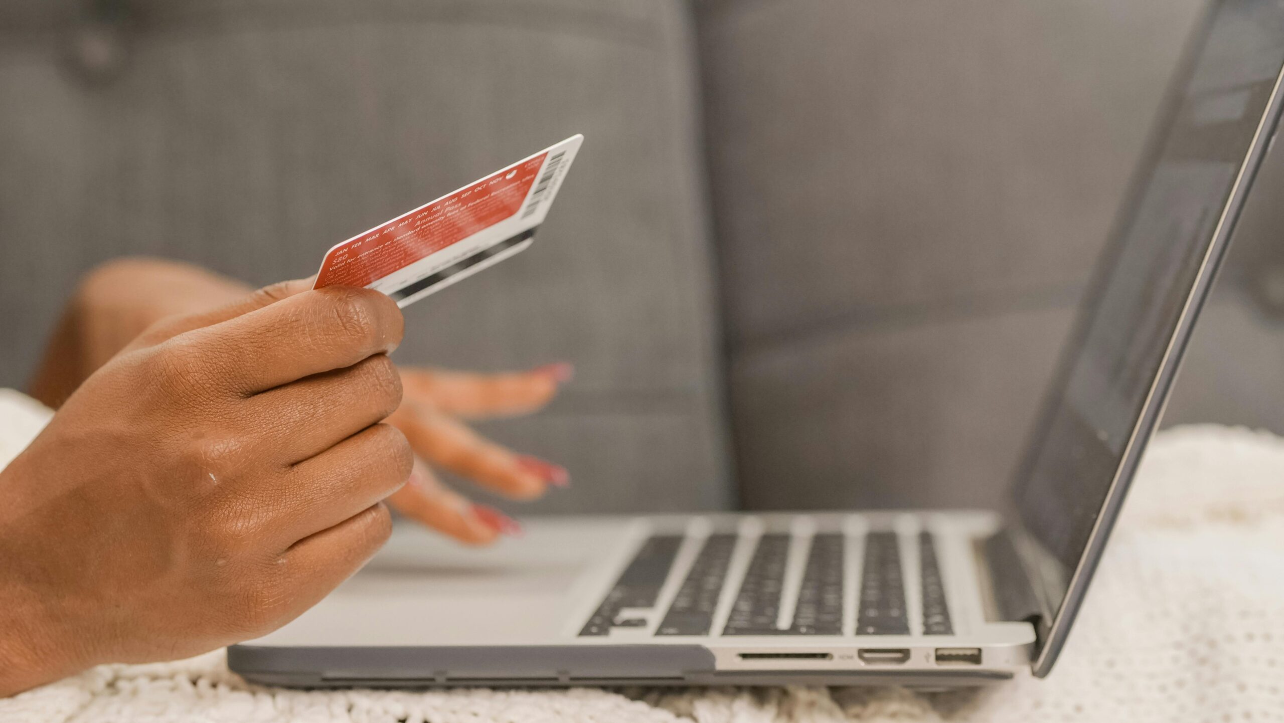7 Remote Job Scams to Avoid at All Costs: Picture of a lady making a payment with a debit card on her laptop