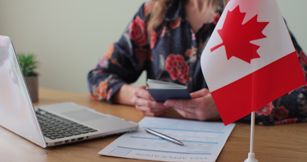 Online vs In-Person Canada Visa Application: Picture of a Canadian woman consular officer giving passport to male immigrant, work visa, citizenship.