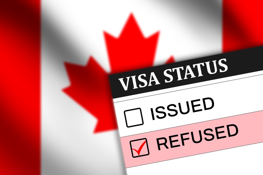 Canada Visa Rejection Triggers to Avoid at All Costs: Canada visa refused status on paper with red tick mark in the box and waving flag in the backdrop 