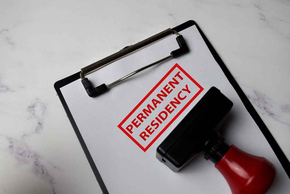 Temporary Work Permit vs Permanent Residency: Red Handle Rubber Stamper and Permanent Residency text isolated on White Background.