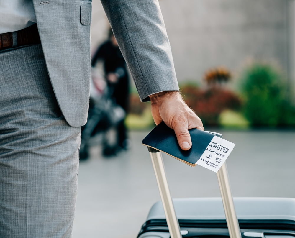 Travel Insurance for Canada: An Anonymous Businessman Holding Passport and Luggage at the Airport