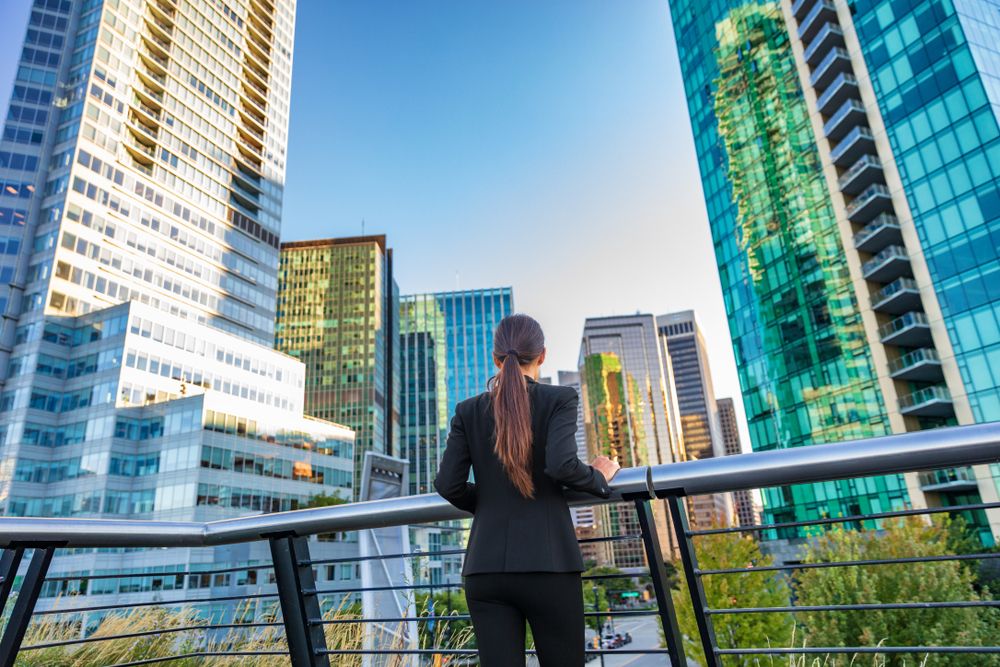 Working in Canada vs Working in the US: Businesswoman in city center looking at the view of skyline skyscrapers in Vancouver downtown, Canada. 