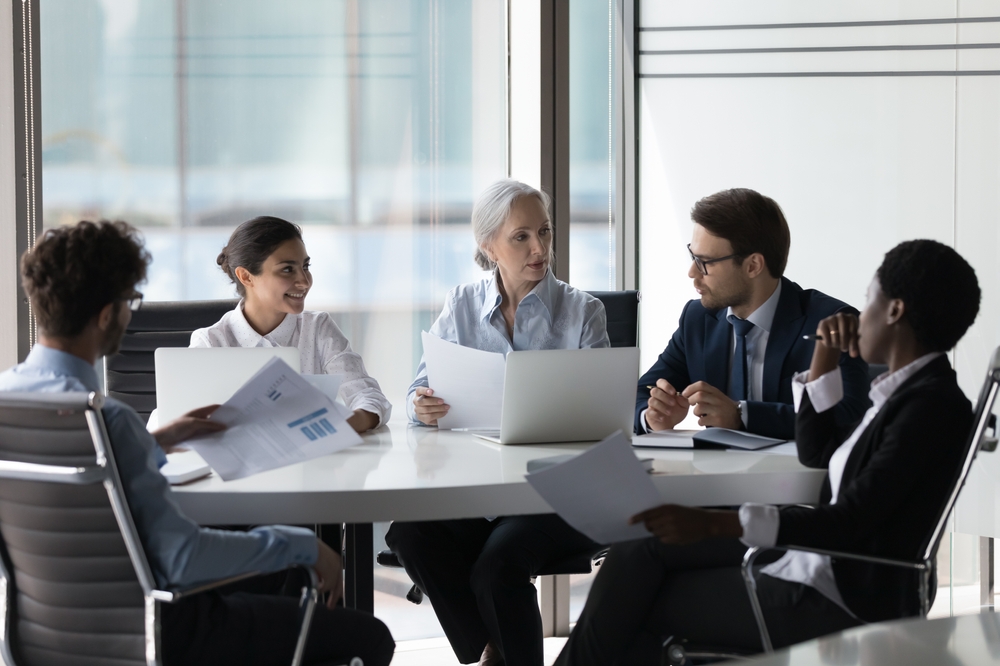 Associate Bankers Job: Diverse corporate staff discuss reports shown in charts and graphs, analyze financial stats, do paperwork involved in project analysis during meetings in the boardroom. 