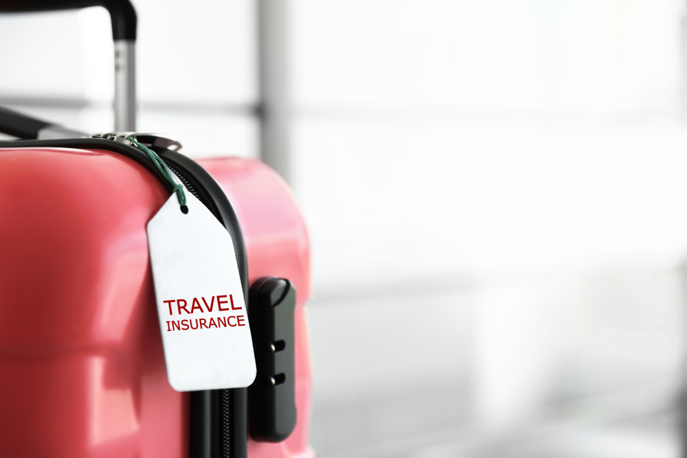 Travel Insurance for Canada vs Health Insurance for Canada: Stylish suitcase with travel insurance label on blurred background, closeup. Space for text 