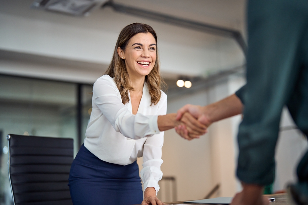 Negotiating a Higher Salary in the UK Job Market: Happy Mid Aged Business Woman Manager Handshaking Greeting Client